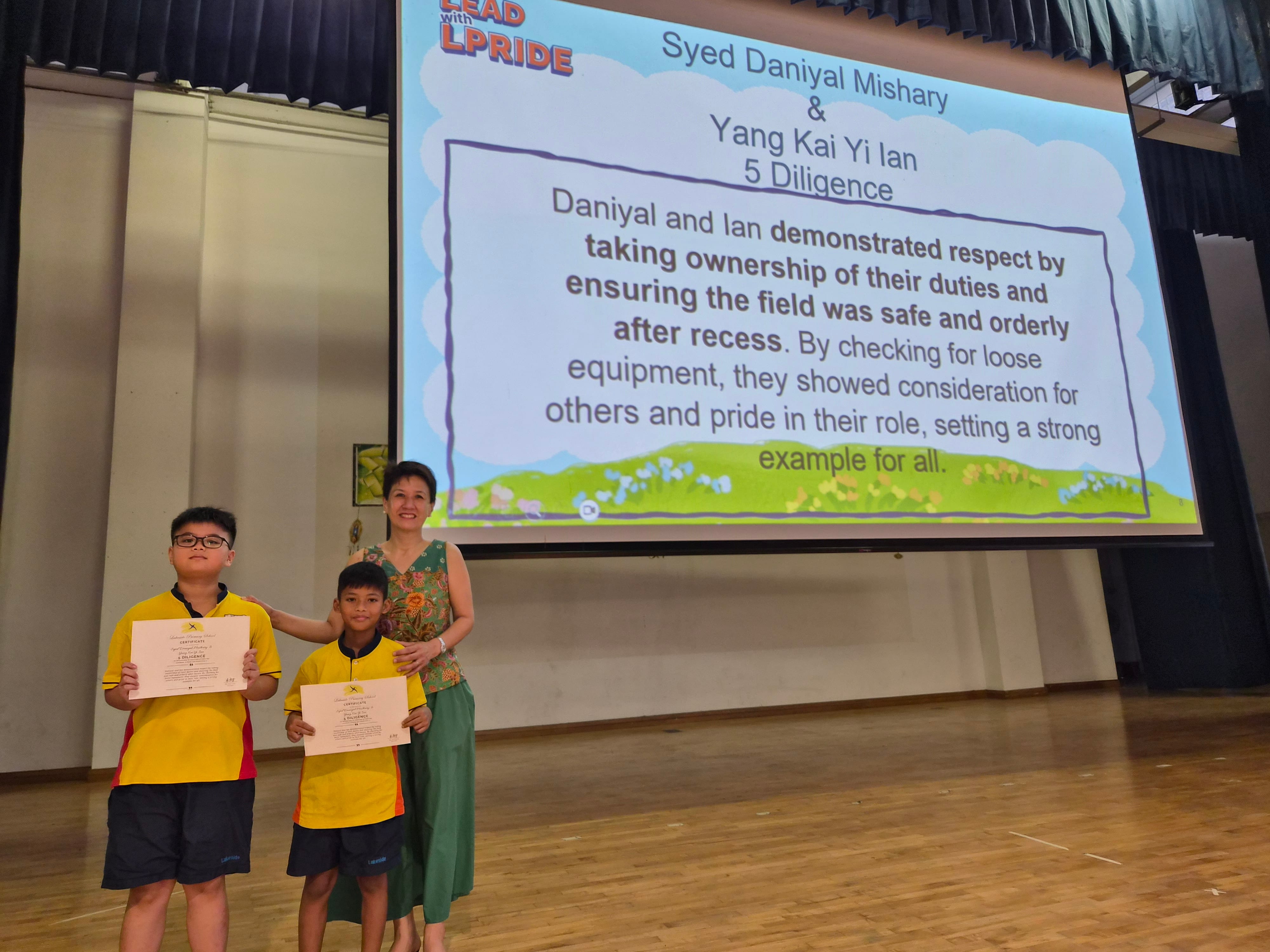 Syed Daniyal Mishary & Yang Kai Yi Ian receiving their certificates from Mrs Liang on stage
